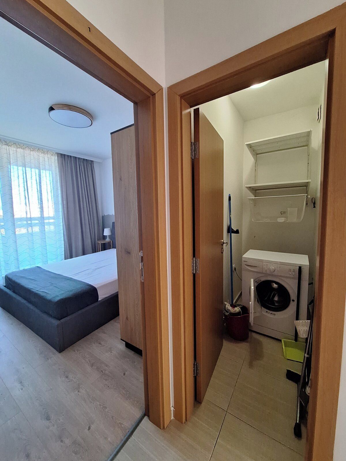 A hotel room with a bed, a washing machine, and a small bathroom.