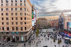 A bustling urban square with historic buildings, a large Samsung advertisement, and a crowd of people. - Hostal El Carmen (Madrid)
