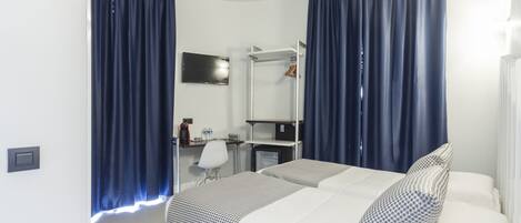 A hotel room with a bed, a desk, a chair, a mirror, and a television.