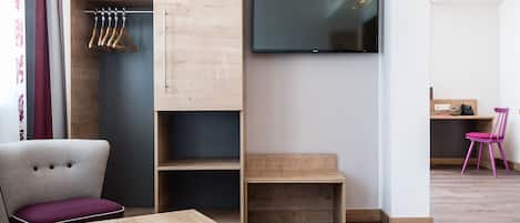 Una habitación moderna con un escritorio de madera, una silla, un televisor y un armario.