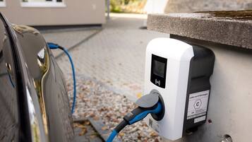 Estació de càrrega per a vehicles elèctrics amb un cable connectat a un cotxe.