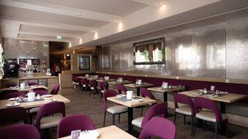 A restaurant with multiple tables and chairs, a bar area, and a counter.