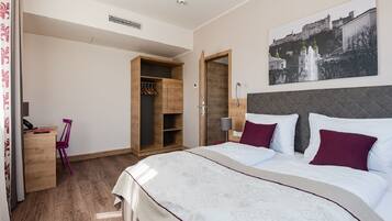 Une chambre à coucher avec un grand lit, une armoire en bois, un bureau avec une chaise et un tableau accroché au mur.