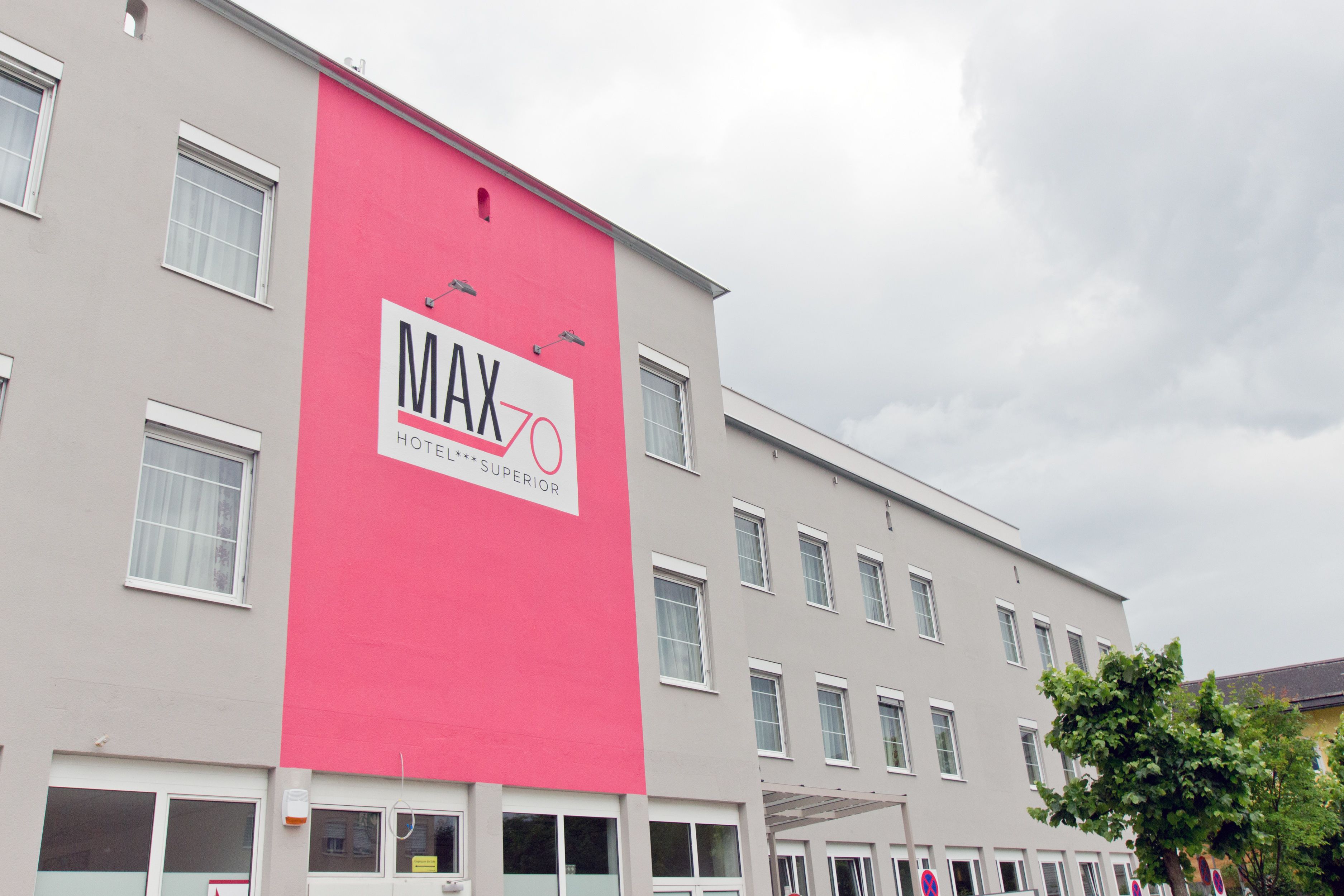 Un edificio de hotel con un letrero rosa grande que dice "MAX 70 HOTEL SUPERIOR".