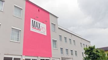 Un edificio de hotel con un letrero rosa grande que dice "MAX 70 HOTEL SUPERIOR".