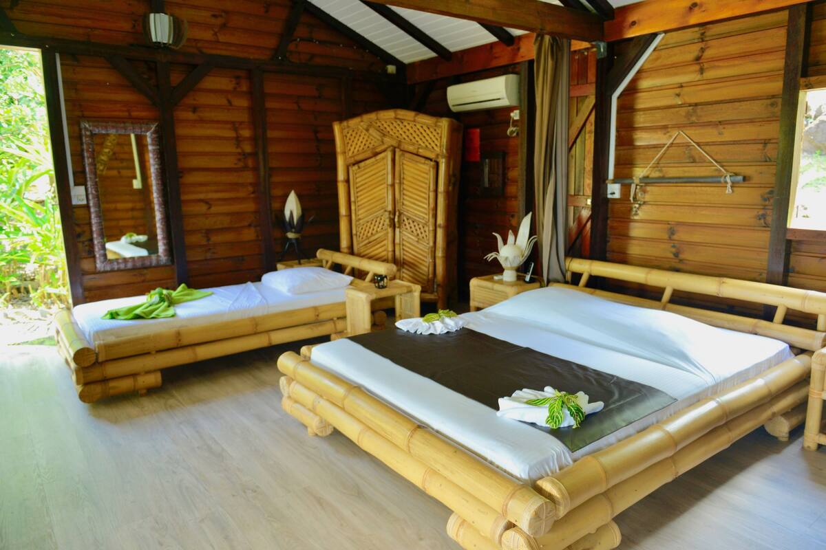 Una cabaña de madera con dos camas individuales, un armario grande y una lámpara colgante.