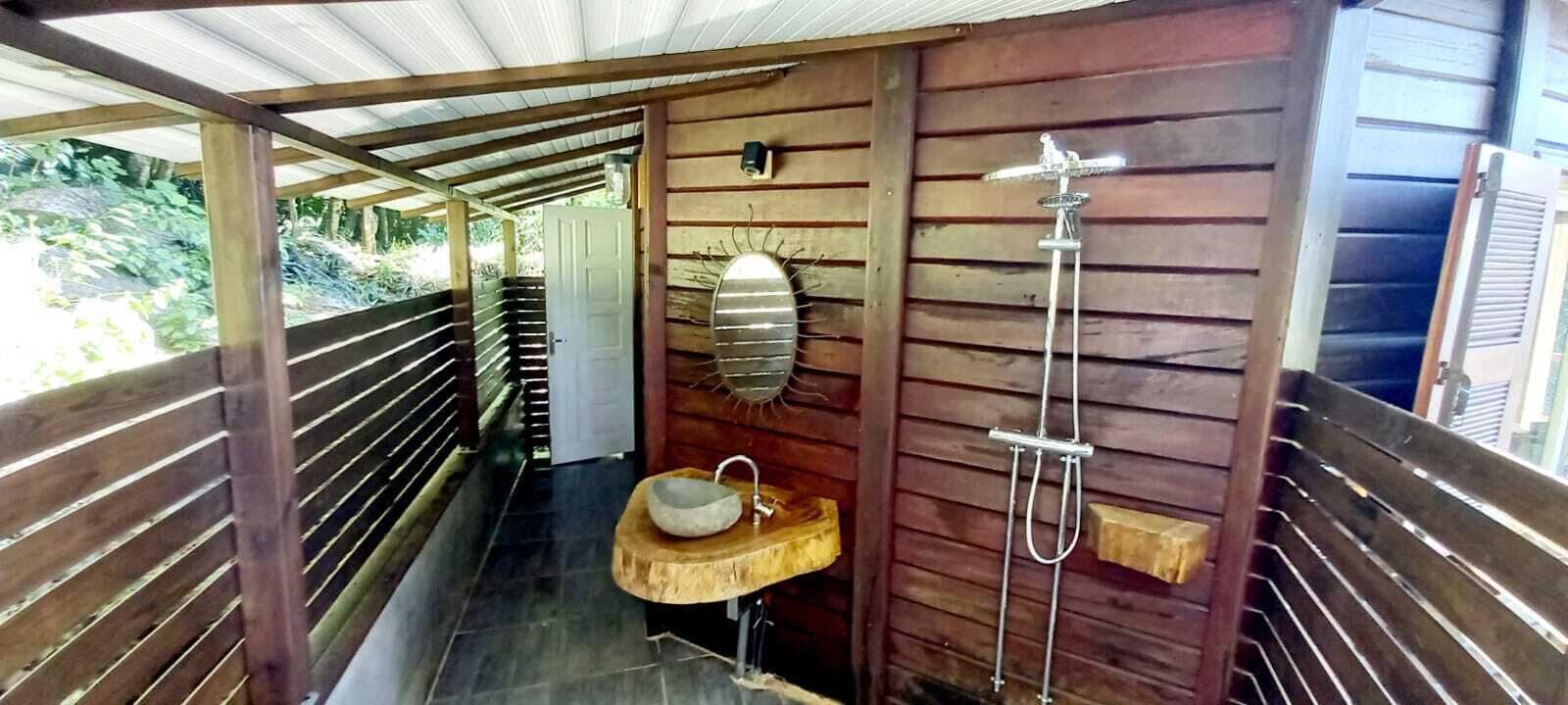 Une cabane en bois dotée d’une salle de bain comprenant un banc en bois, un lavabo et une douche.