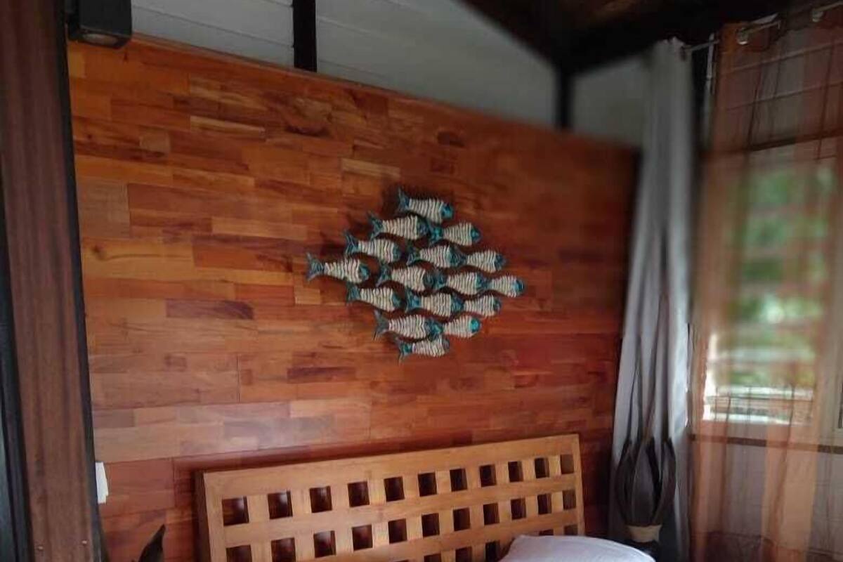 Una cama con estructura de madera y ropa de cama blanca en una habitación con pared de madera y un adorno de pared con forma de pez.