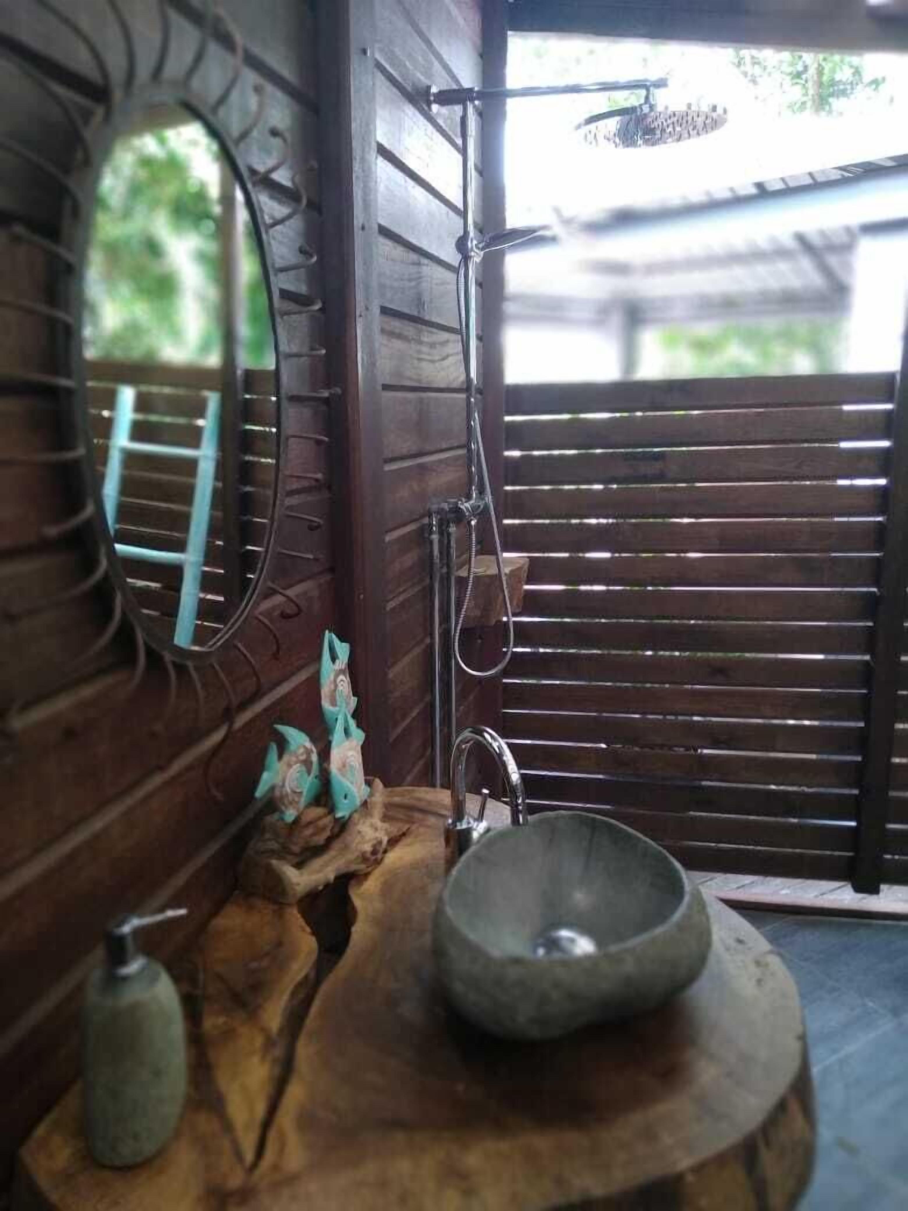 A rustic bathroom with a wooden sink, a mirror, and a shower area.