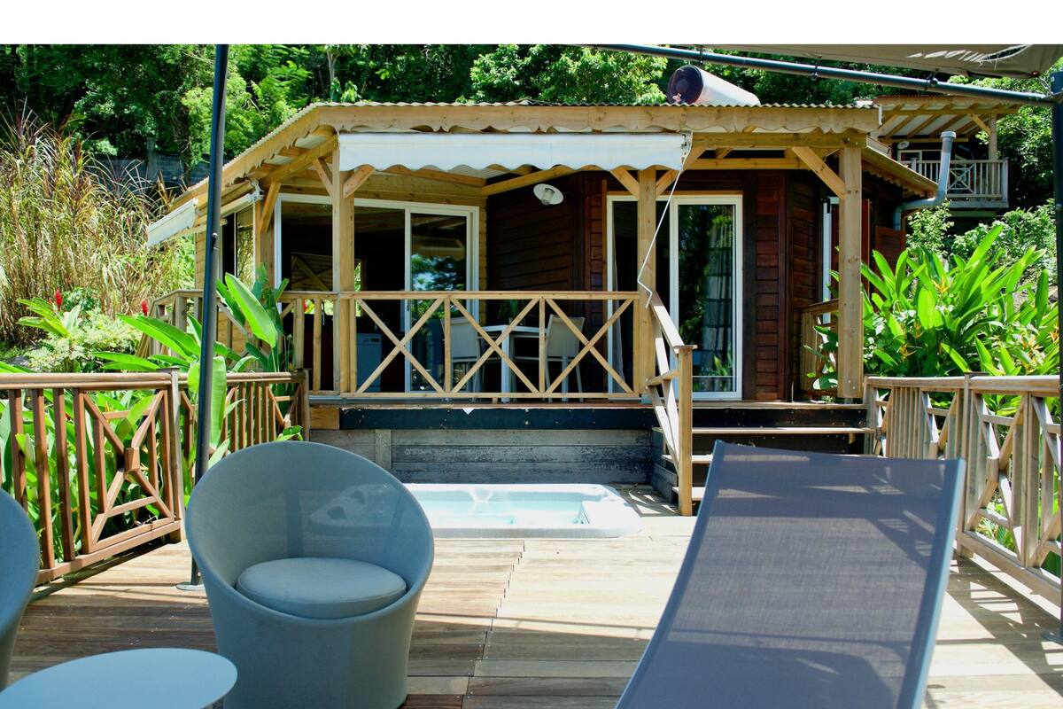 Una cabaña de madera con un porche, mobiliario exterior y una piscina pequeña.