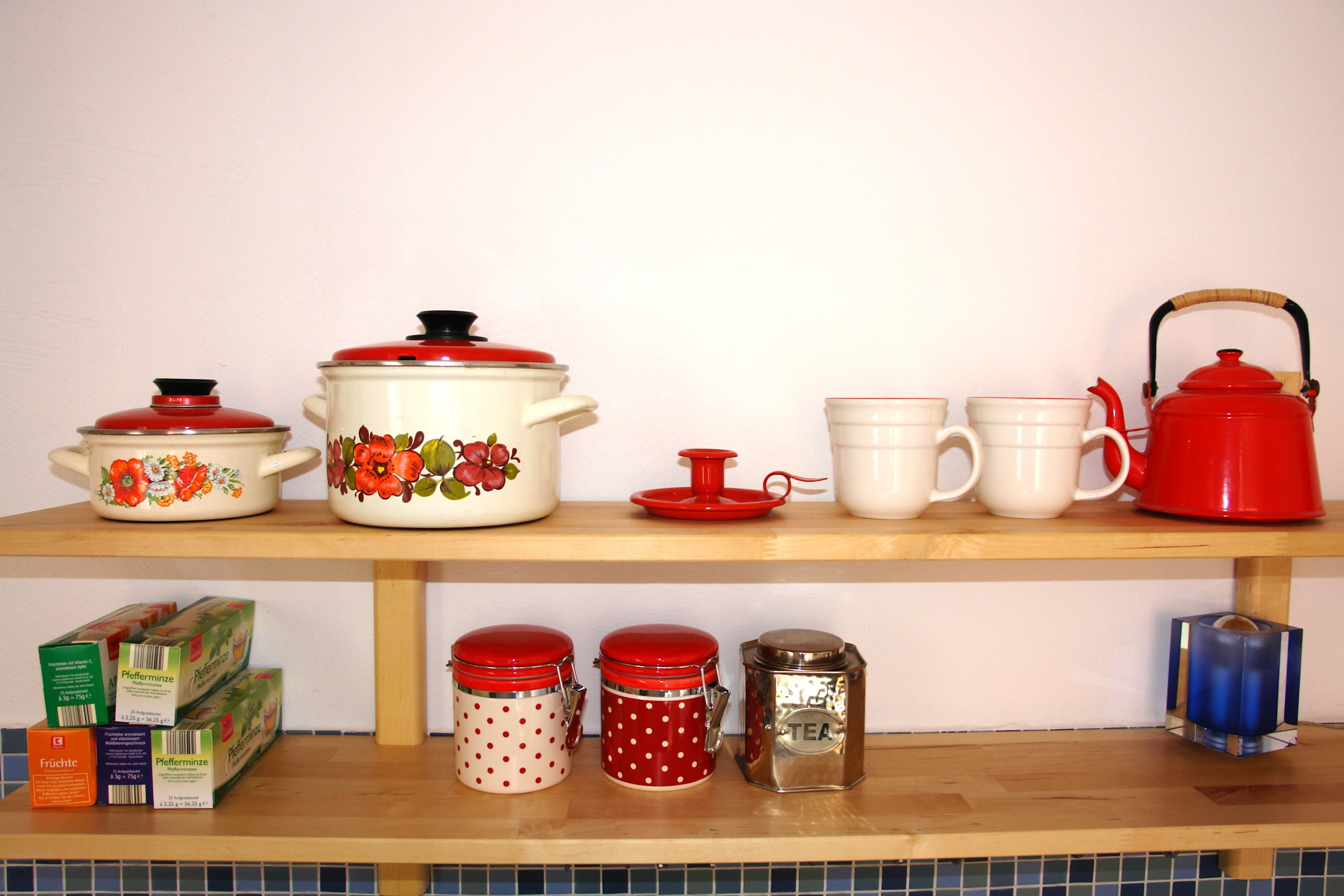 Un estante de cocina con diversos utensilios, incluyendo ollas, sartenes y recipientes de almacenamiento.