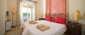 Habitación de hotel con cama, dos lámparas de noche, mesita de noche, escritorio y vistas al exterior.