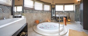 Un baño moderno con una bañera grande, cabina de ducha separada y tocador con lavabo.