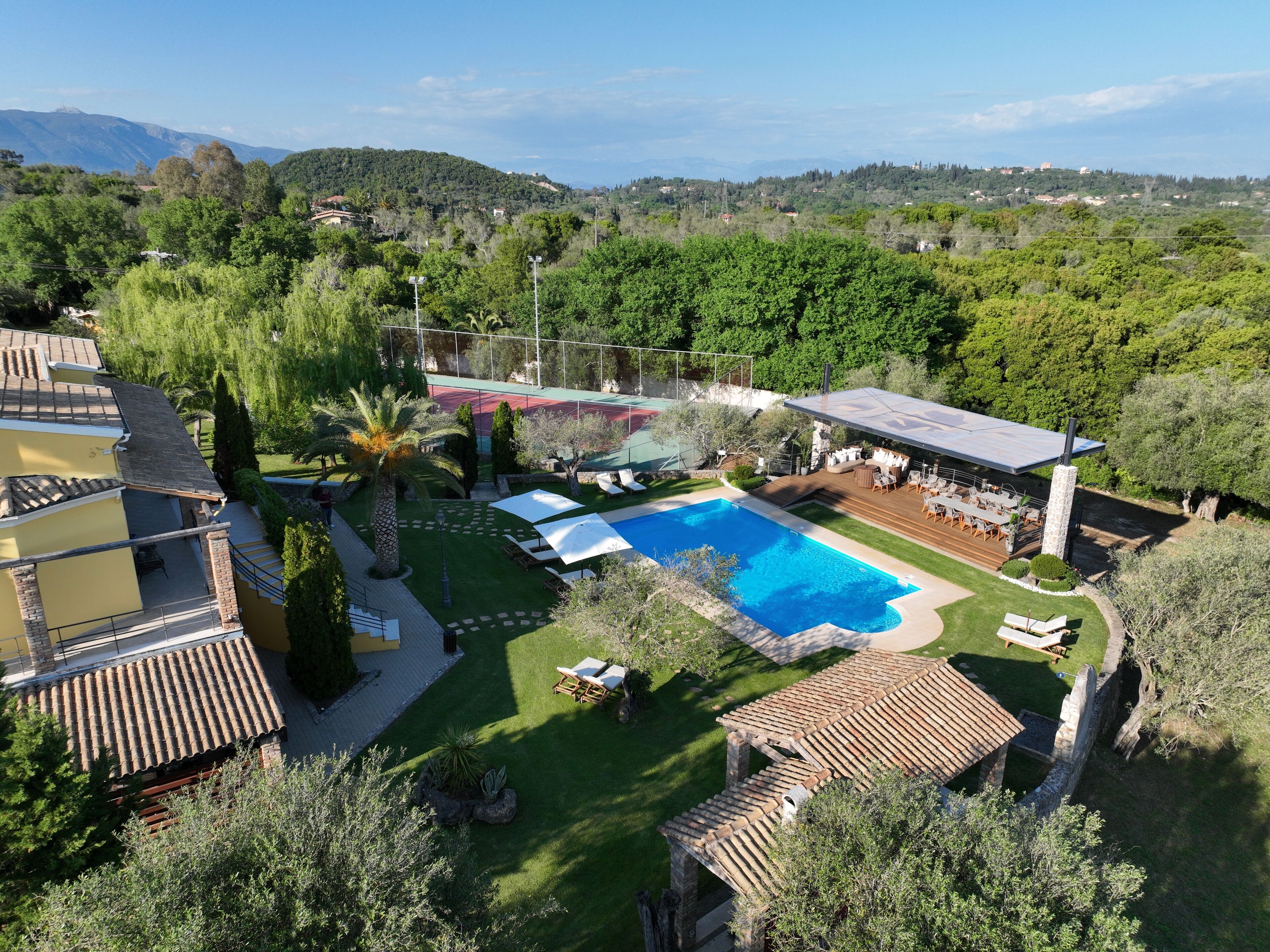 A residential property with a swimming pool, outdoor seating, and a view of the surrounding hills.