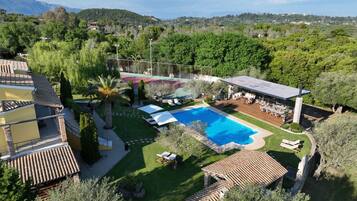 A residential property with a swimming pool, outdoor seating, and a view of the surrounding hills.