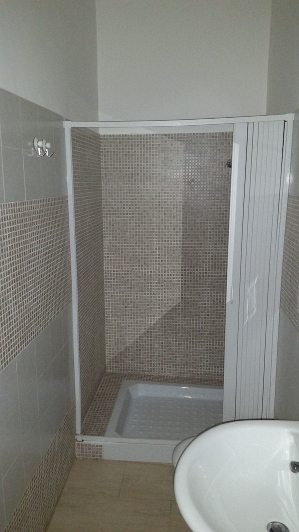A bathroom with a shower area, tiled walls, and a sink.