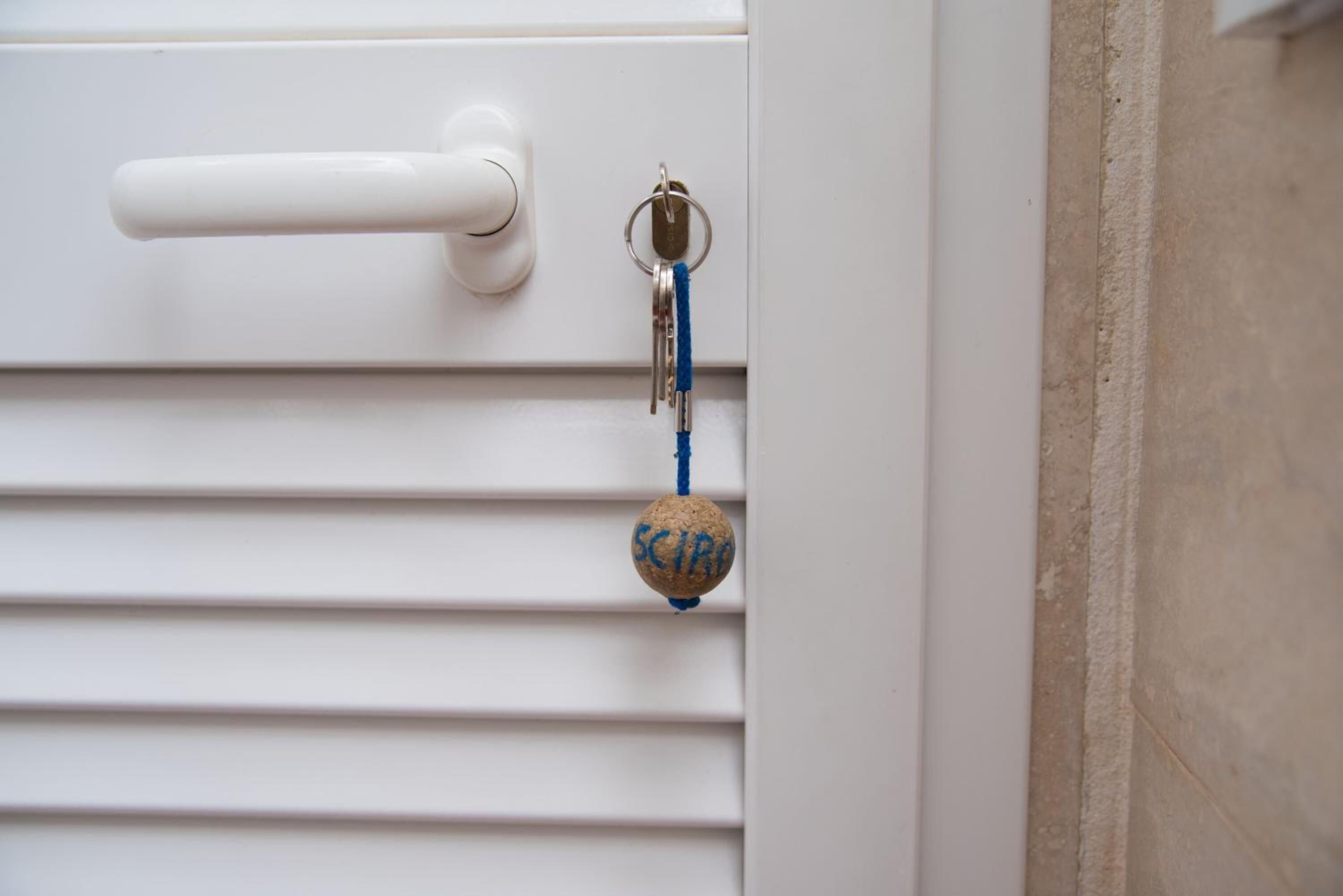 Una puerta blanca con una llave y un llavero azul.