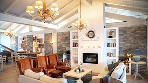 Amplia sala de estar con sofás de cuero, chimenea y un muro decorativo de piedra.