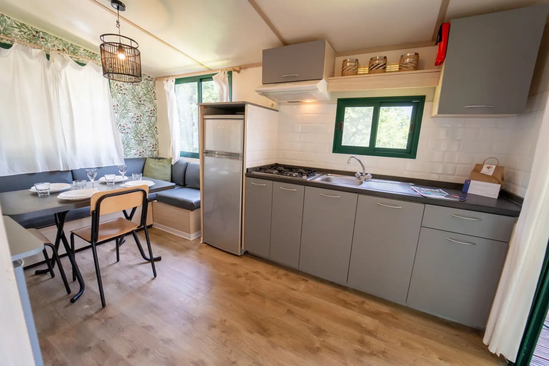 Une cuisine compacte dotée d’une cuisinière intégrée, d’un réfrigérateur et de meubles de couleur grise.