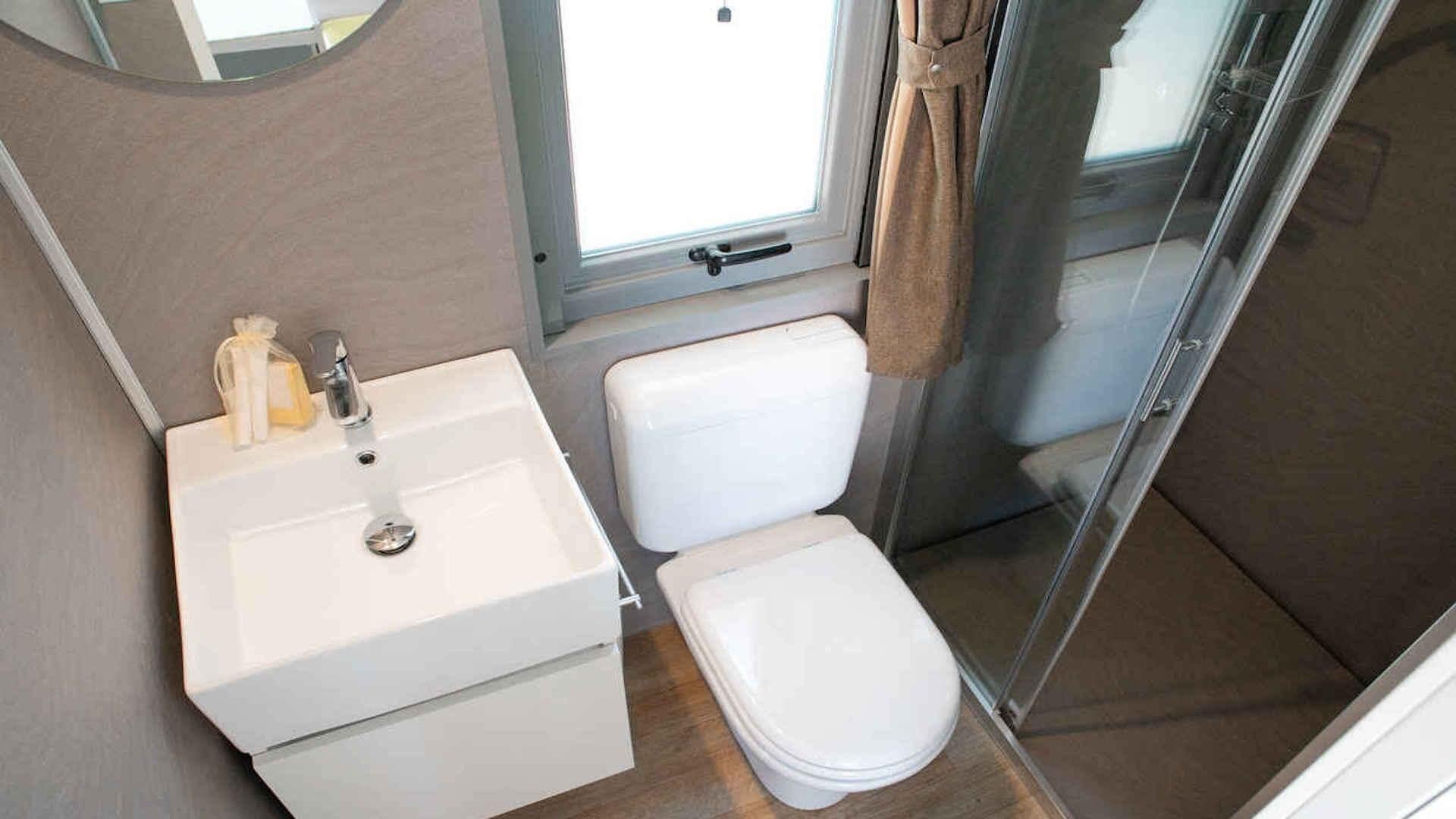 A compact bathroom with a white sink, toilet, and shower.
