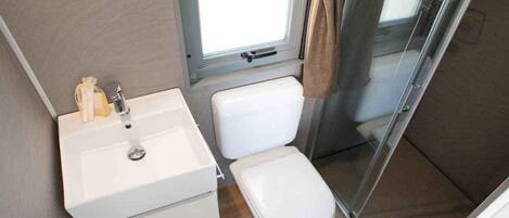 A compact bathroom with a white sink, toilet, and shower.