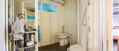 A bathroom with a glass-enclosed shower, a toilet, and a vanity with a towel rack and toiletries.