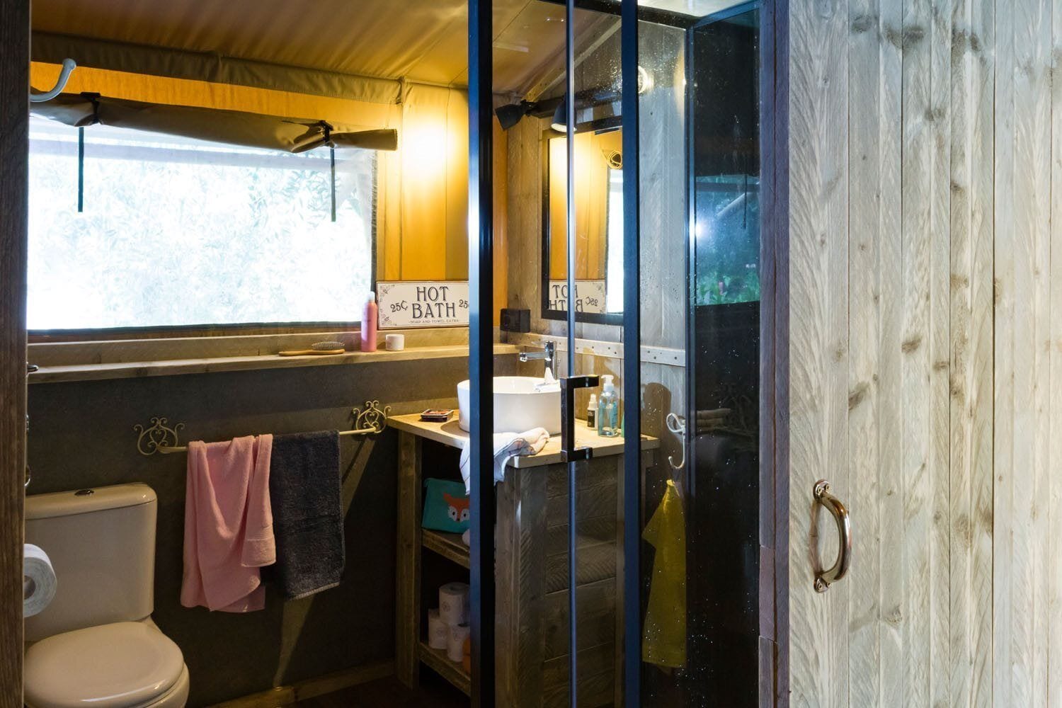 Een kleine badkamer met toilet, wastafel en een raam.