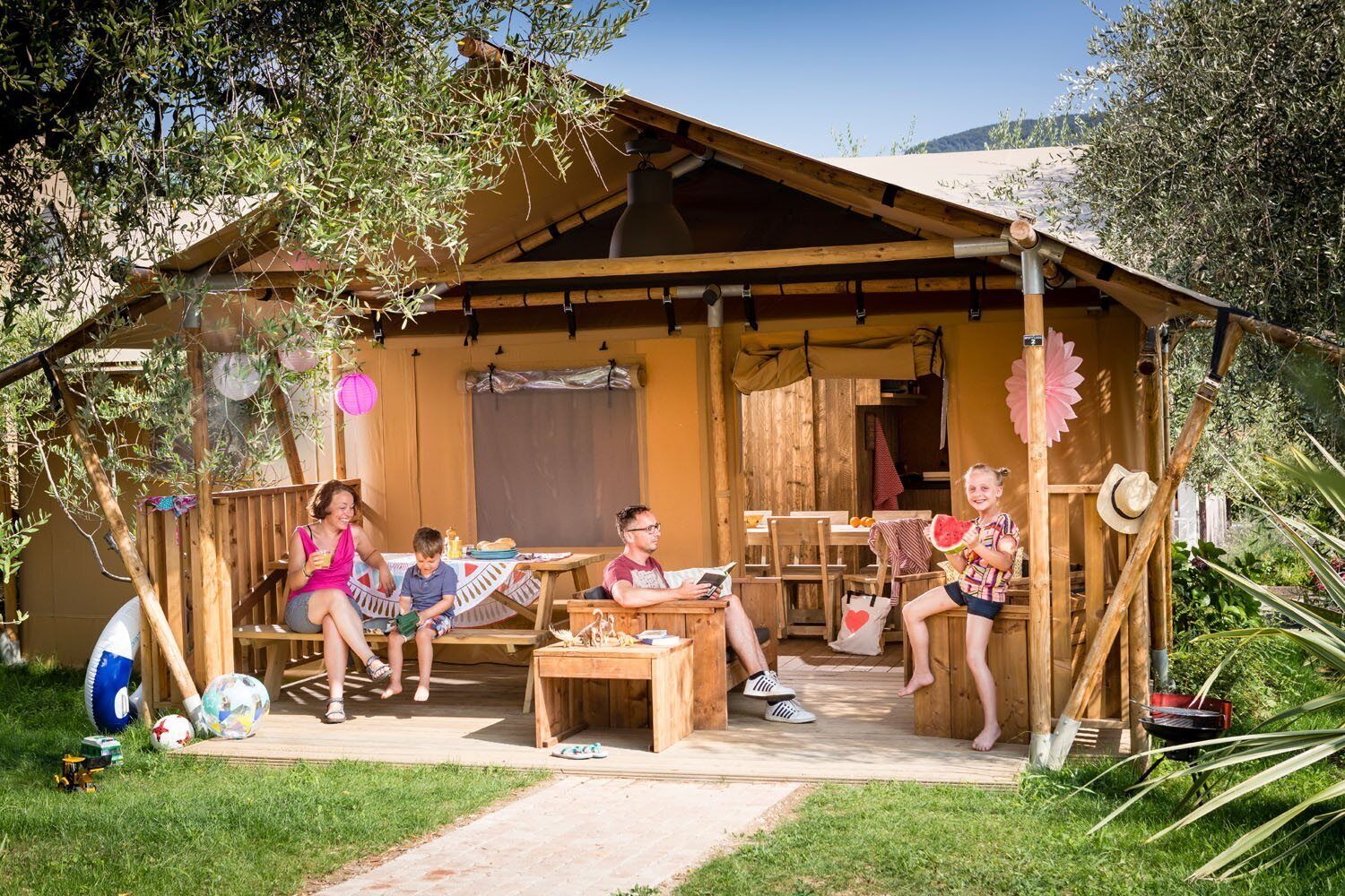 A rustic wooden cabin with a covered patio, outdoor seating, and a barbecue grill.