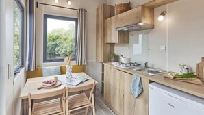 Una cocina compacta con zona de comedor, armarios de madera, estufa a gas y un lavamanos.