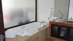 Un baño moderno con una bañera grande, una zona de ducha separada, un tocador con lavabo y un espejo amplio.