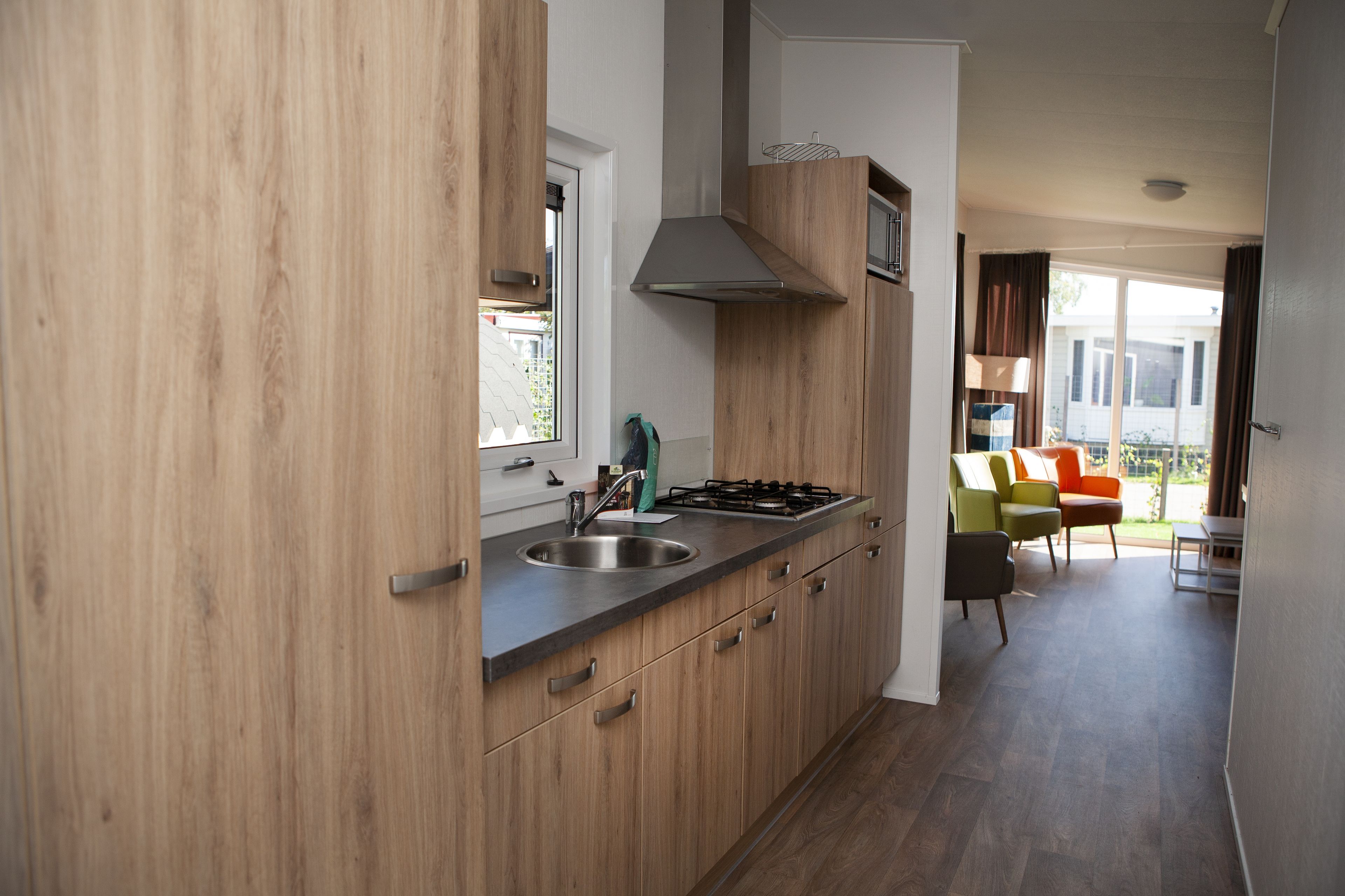 A modern kitchen with wooden cabinets, a stainless steel sink, and a gas stove.