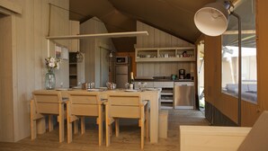 Una cocina con armarios de madera, una mesa de comedor con sillas y una lámpara colgante.