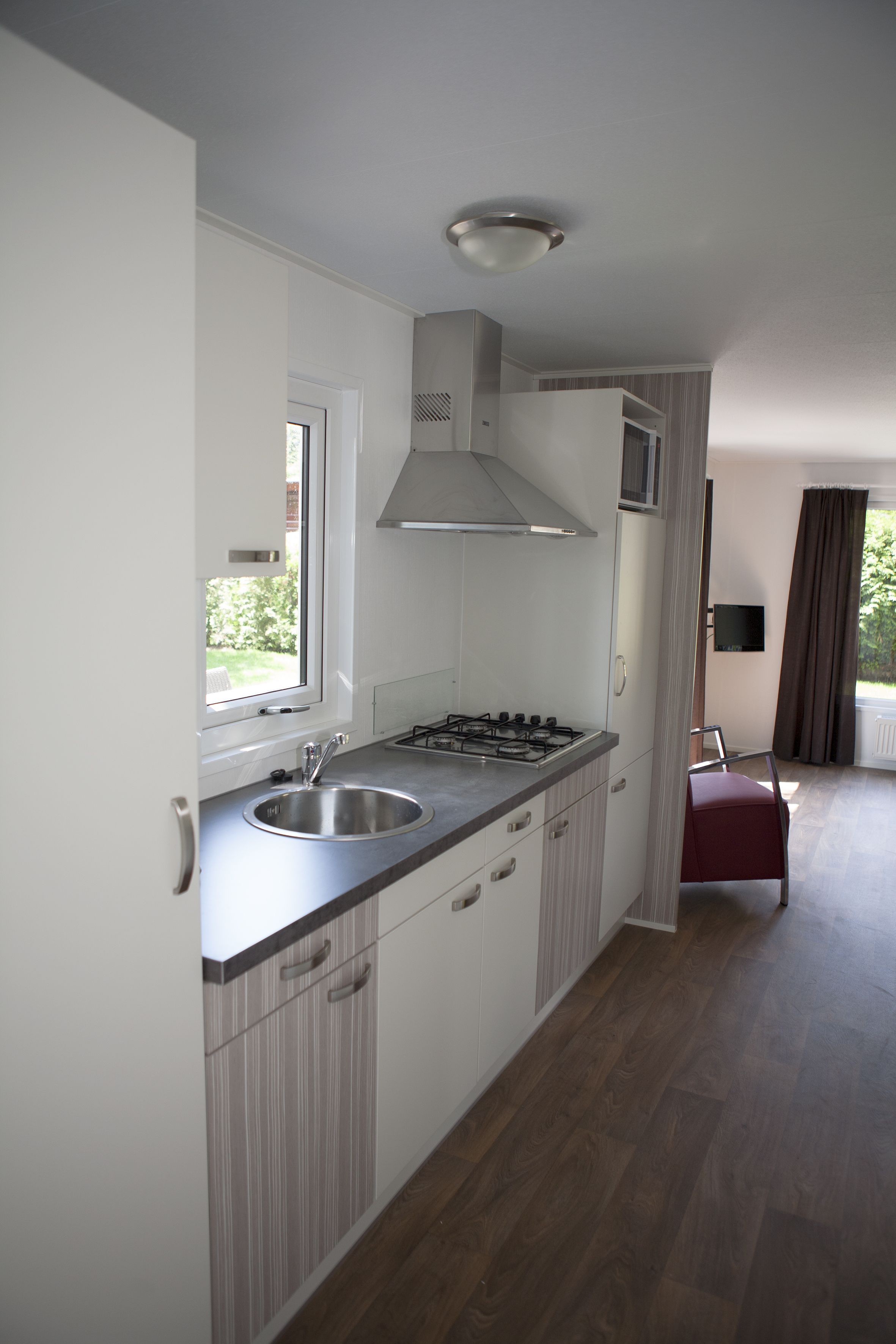 A modern kitchen with a gas stove, stainless steel sink, and a window providing natural light.