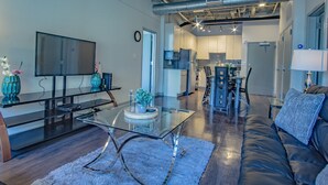 A modern living room with a glass coffee table, a flat-screen TV, and a leather sofa. - Heaven on Midtown Fully Furnished Apts (Atlanta)