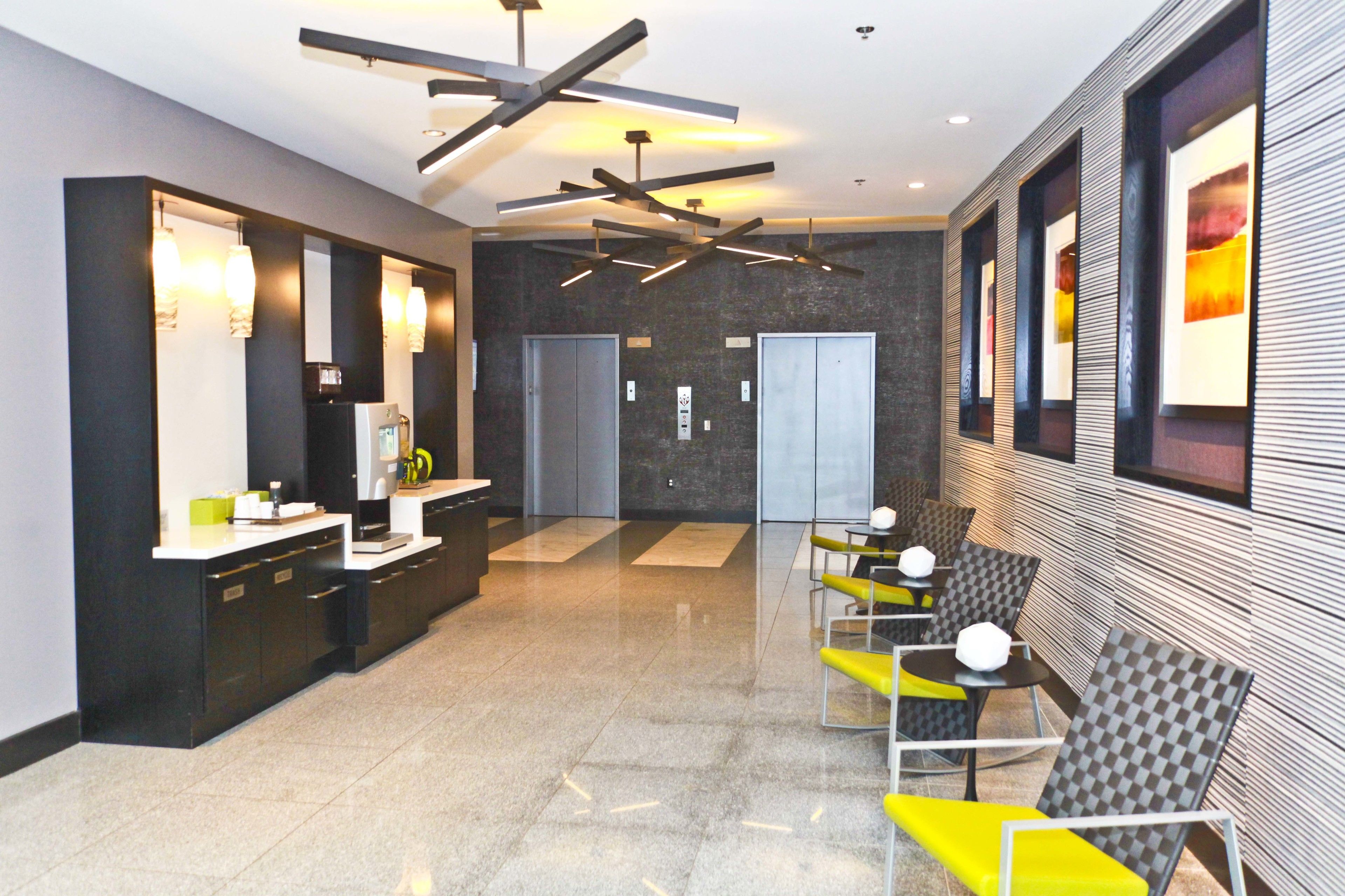 A modern lobby with a reception desk, seating area, and elevators.