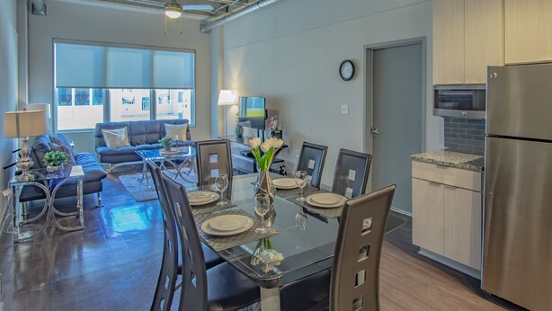 A modern kitchen with stainless steel appliances, a dining area with a glass table, and a living room with a sofa and TV. - Heaven on Midtown Fully Furnished Apts (Atlanta)