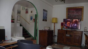 A living room with a TV, a desk, a chair, a lamp, and a staircase. - Hôtel La Lubiane (Vence)