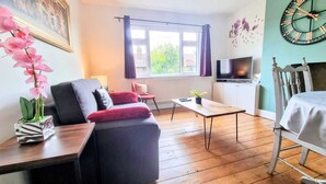 A living room with a sofa, a TV, a coffee table, and a window with curtains. - Stunning Central Richmond with garden (Richmond)
