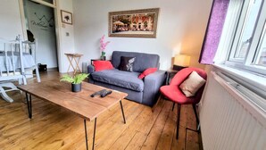 A living room with a grey sofa, red armchair, wooden coffee table, and a framed picture on the wall. - Stunning Central Richmond with garden (Richmond)