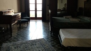 Una habitación con cama, escritorio, silla y un amplio ventanal.