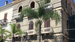 Un edificio histórico con ventanas arqueadas, una entrada central y un letrero del restaurante 'Trattoria La Casalinga'.