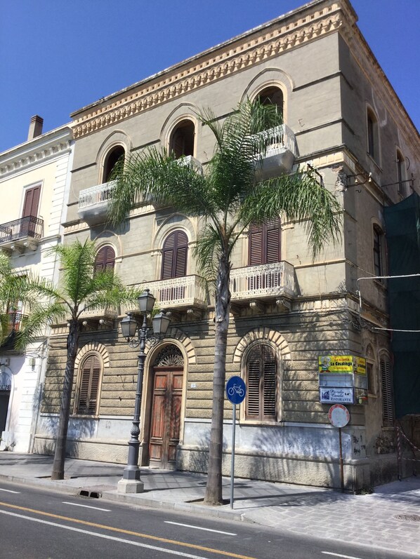 A historic building with arched windows, a central entrance, and a sign for 'Trattoria La Casalinga' restaurant.