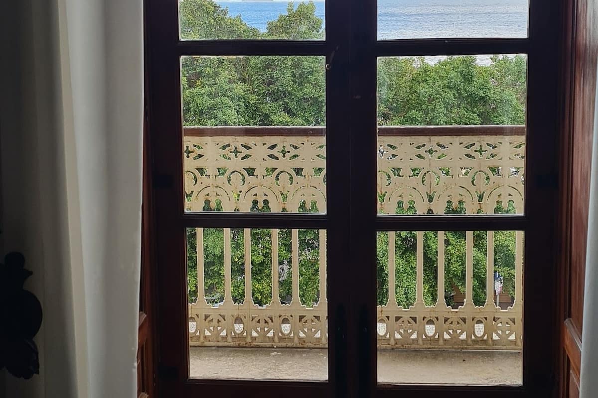A room with a large arched window overlooking a balcony with a decorative railing.