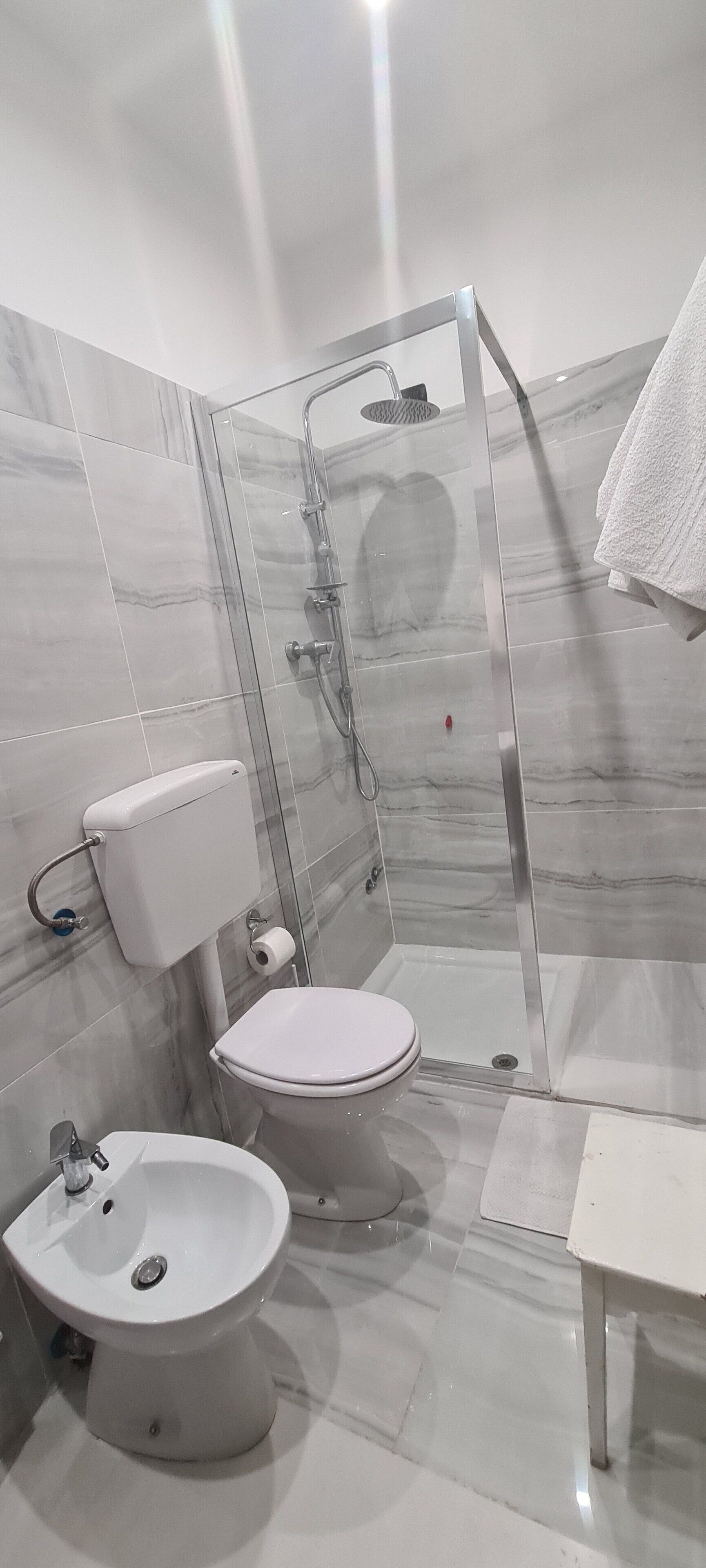 Uma casa de banho moderna com sanita, bidé e cabine de duche com vidro.