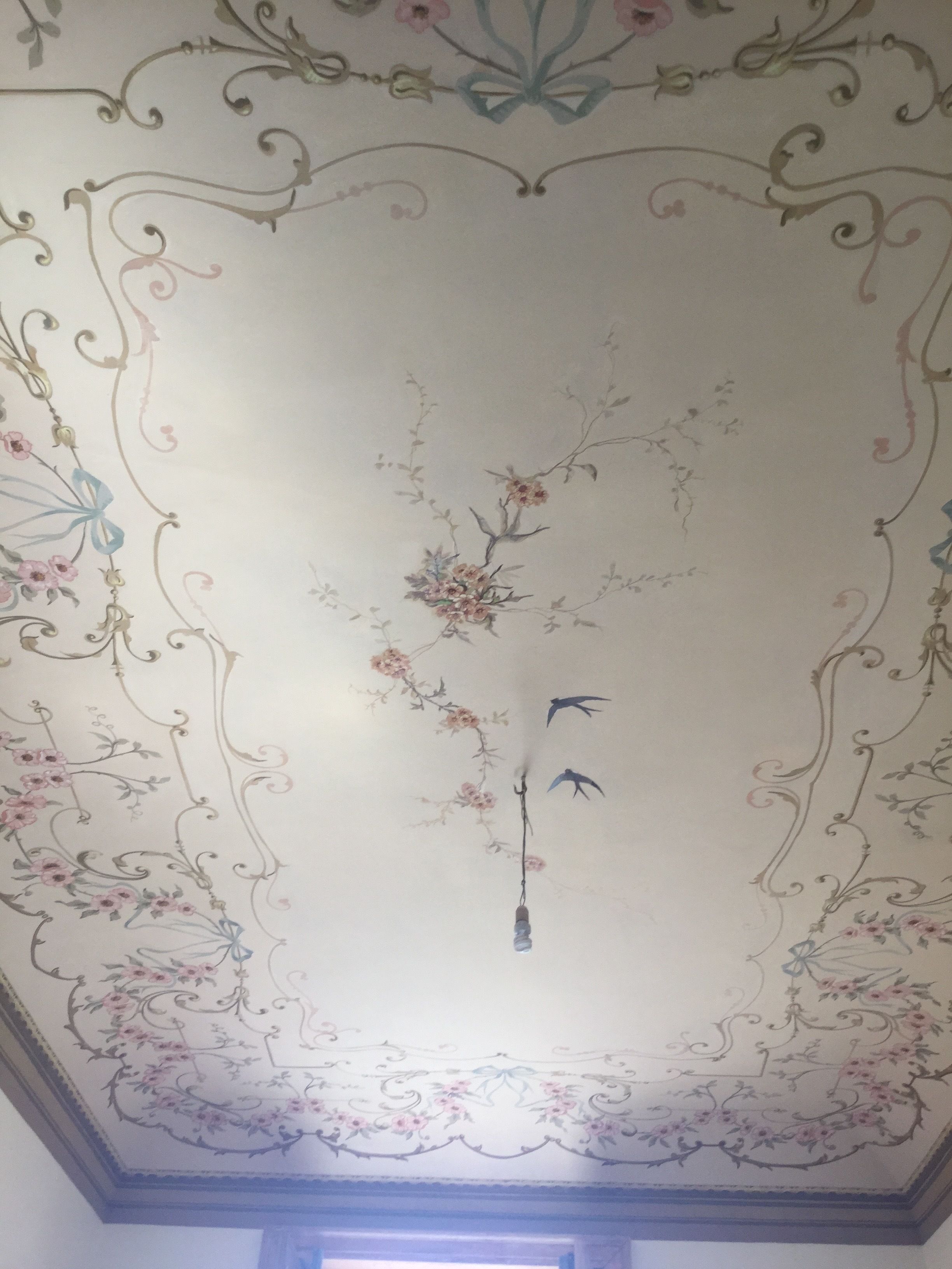 Un soffitto decorato con motivi floreali e immagini di uccelli.