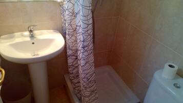 Un baño con un lavamanos blanco, un inodoro y una cortina de ducha con estampado de árboles.