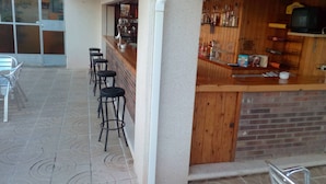A bar area with stools, a counter, and a television. - Hostal Lleida (Calafell)