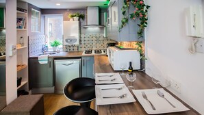 Une cuisine compacte avec un coin repas, équipée d’un lave-vaisselle, d’une cuisinière et d’une petite table pour deux personnes.
