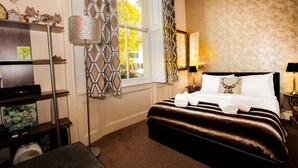 Une chambre d’hôtel avec un lit, un bureau, une lampe et une fenêtre avec des rideaux.