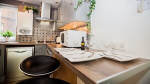 Une cuisine moderne équipée d’un four à micro-ondes, d’un grille-pain et d’une bouteille de vin posée sur le plan de travail.